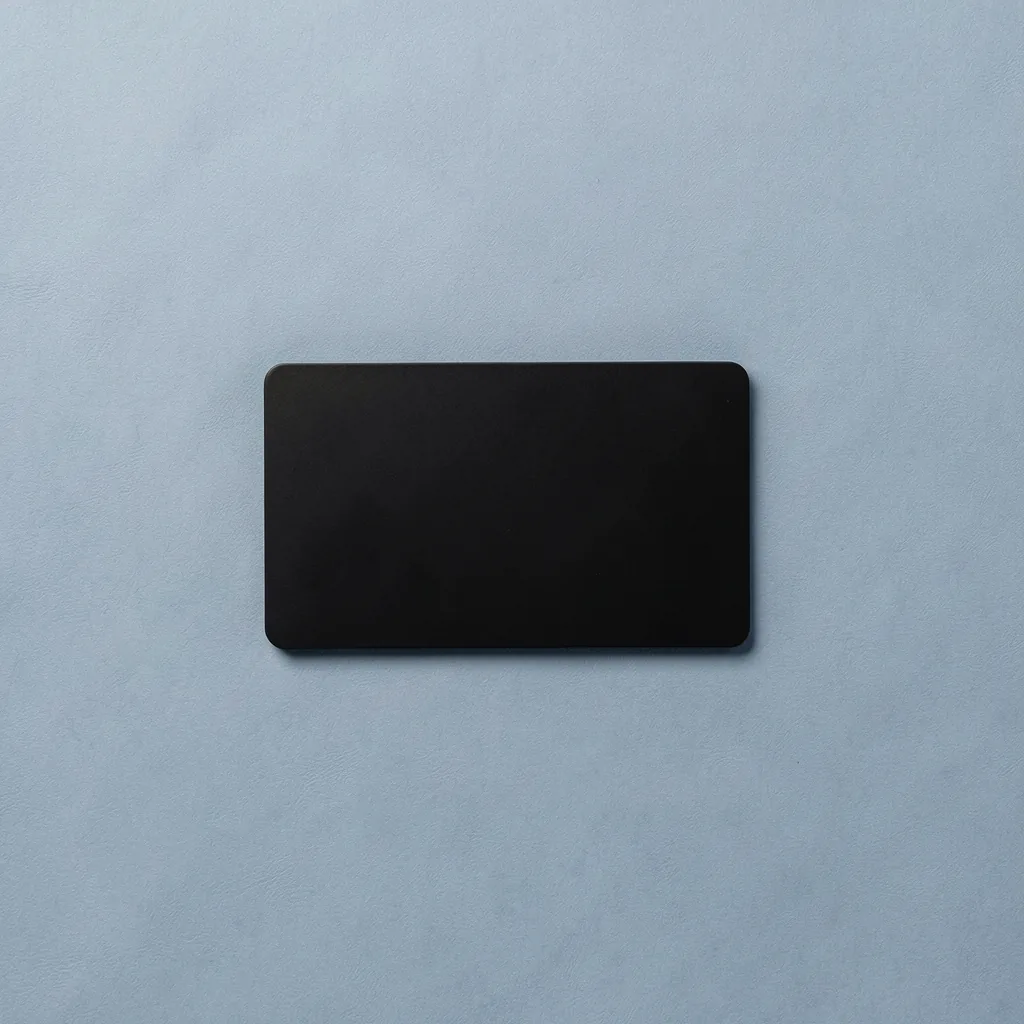 Matte-black payment card on a blue-grey backdrop